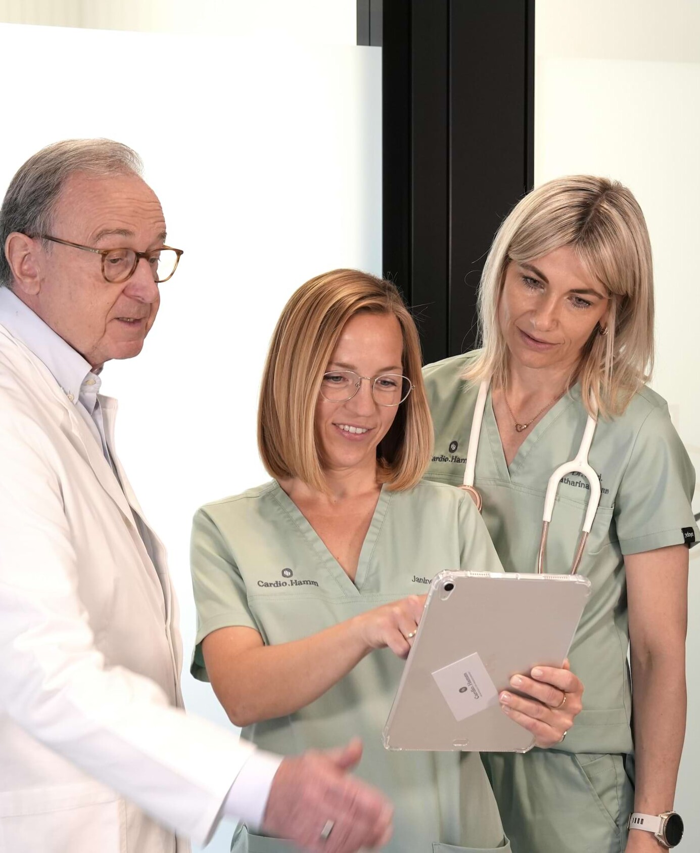 Foto: Prof. Dr. med. Christian Hamm (links), Janine Kern (mittig) und Dr. med. Catharina Hamm (rechts) schauen gemeinsam auf ein Tablet