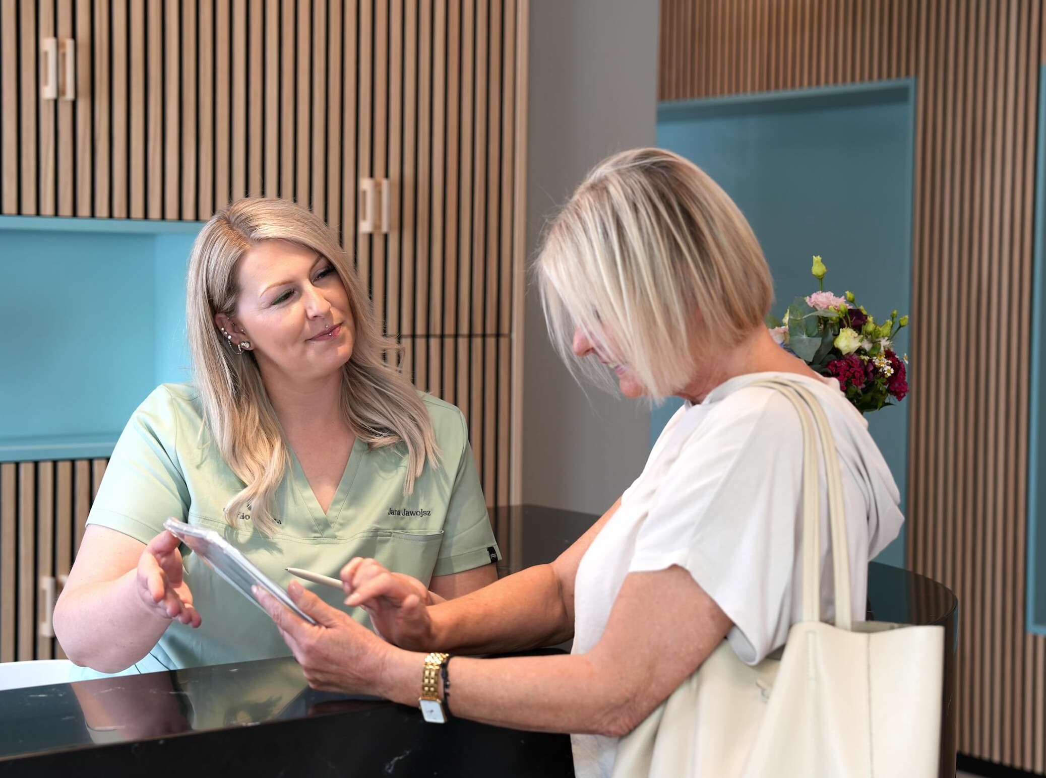 Foto: Eine Patientin wird von Jana an der Rezeption empfangen